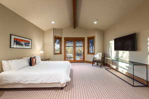 Carpeted bedroom featuring vaulted ceiling with beams and access to exterior