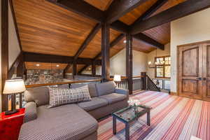 Living room with beamed ceiling, high vaulted ceiling, an inviting chandelier, and wood ceiling