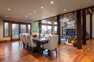 Dining space with hardwood / wood-style floors, a wealth of natural light, and a stone fireplace