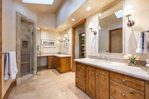 Bathroom featuring a skylight, vanity, and a shower with shower door