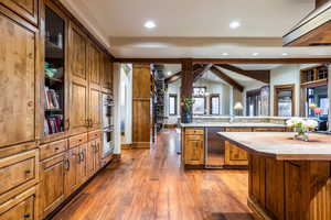 Kitchen featuring a kitchen island, lofted ceiling with beams, wooden counters, dark wood-type flooring, and stainless steel appliances