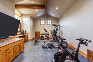 Exercise room featuring vaulted ceiling and carpet