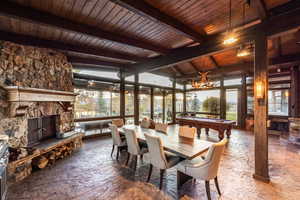 Dining space with beam ceiling, a stone fireplace, wood ceiling, and billiards