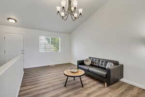 Living room featuring wood-type flooring, high vaulted ceiling, and an inviting chandelier