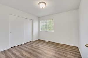 Unfurnished bedroom featuring a closet and hardwood / wood-style flooring