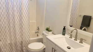 Full bathroom with toilet, vanity, and bathing tub / shower combination