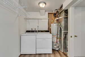 Laundry area featuring washer and clothes dryer, light hardwood / wood-style floors, and gas water heater