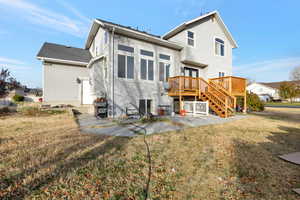 Back of property featuring a yard, a patio, and a wooden deck