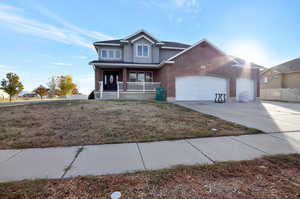 View of property with a front yard, a porch, and a garage