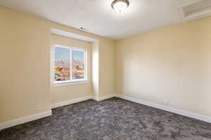 Spare room with dark carpet and a textured ceiling