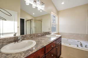 Bathroom featuring vanity, lofted ceiling, and independent shower and bath