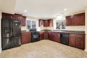 Kitchen with black appliances, a healthy amount of sunlight, light tile patterned floors, and sink