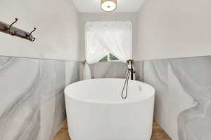 Bathroom with a bathing tub, tile walls, and hardwood / wood-style floors