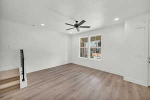 Empty room featuring light hardwood / wood-style flooring, ceiling fan, and a textured ceiling