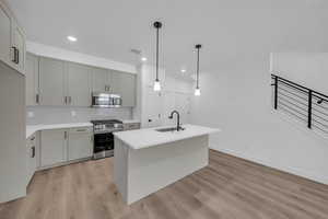 Kitchen featuring light hardwood / wood-style flooring, gray cabinetry, sink, and appliances with stainless steel finishes