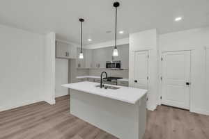 Kitchen with an island with sink, sink, appliances with stainless steel finishes, and light wood-type flooring