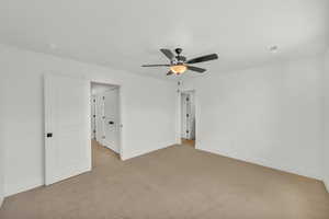 Empty room with ceiling fan and light colored carpet