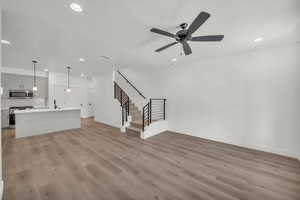 Unfurnished living room with a textured ceiling, light wood-type flooring, and ceiling fan