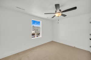 Carpeted empty room featuring ceiling fan