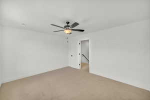 Carpeted empty room featuring ceiling fan