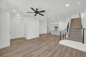 Unfurnished living room featuring a textured ceiling, light hardwood / wood-style flooring, and ceiling fan