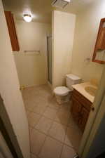 Bathroom featuring vanity, a textured ceiling, tile patterned floors, and a shower with shower door