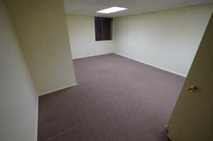 Carpeted spare room featuring a paneled ceiling