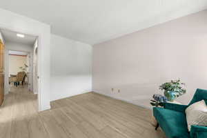 Living area featuring light wood-type flooring and a textured ceiling