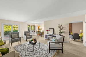 Living room with vaulted ceiling, an inviting chandelier, and light hardwood / wood-style flooring