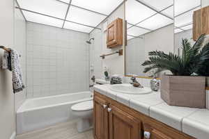 Full bathroom featuring hardwood / wood-style floors, vanity, toilet, and tiled shower / bath combo