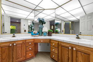 Bathroom with tasteful backsplash, a paneled ceiling, vanity, and hardwood / wood-style flooring