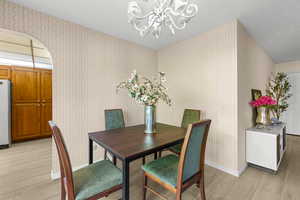 Dining area with light wood-type flooring and an inviting chandelier