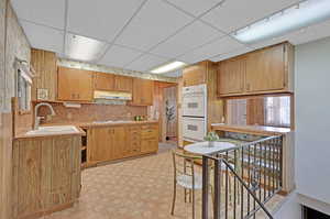 Kitchen featuring white appliances, a drop ceiling, and sink