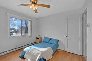 Bedroom with a baseboard radiator, light hardwood / wood-style flooring, and ceiling fan