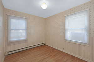 Empty room featuring hardwood / wood-style flooring and a baseboard radiator