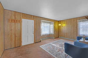 Interior space with carpet flooring, wooden walls, and a baseboard radiator