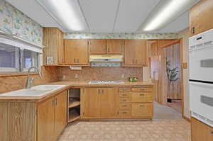 Kitchen featuring white appliances, sink, and tasteful backsplash