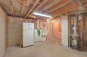 Basement featuring white refrigerator and electric panel