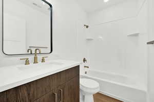 Full bathroom featuring vanity, toilet, wood-type flooring, and tub / shower combination