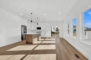 Kitchen featuring white cabinetry, a kitchen island with sink, a healthy amount of sunlight, and appliances with stainless steel finishes