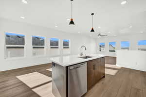 Kitchen featuring sink, an island with sink, stainless steel dishwasher, and light wood-type flooring