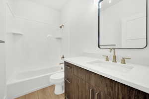 Full bathroom with vanity, toilet, wood-type flooring, and shower / washtub combination