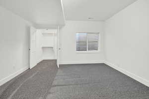 Unfurnished bedroom featuring dark carpet