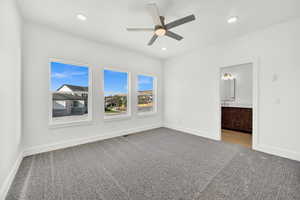 Unfurnished bedroom featuring connected bathroom, ceiling fan, and light carpet