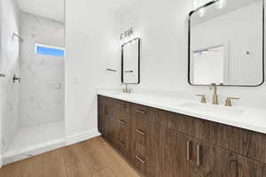 Bathroom featuring vanity, a tile shower, and hardwood / wood-style flooring