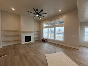 Unfurnished living room with built in shelves, ceiling fan, and hardwood / wood-style floors