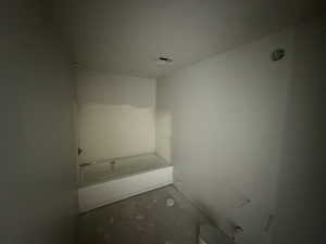 Bathroom featuring a tub to relax in and concrete floors