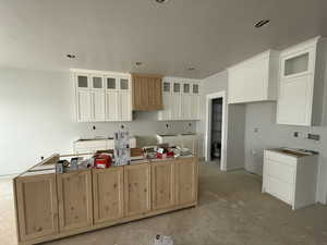 Kitchen featuring white cabinetry, a large island, and a textured ceiling