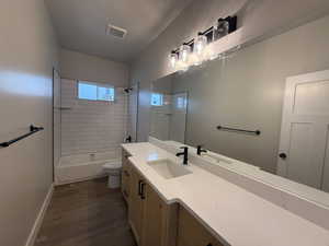 Full bathroom featuring wood-type flooring, vanity, toilet, and tiled shower / bath