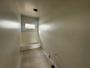 Bathroom with a bathing tub, a textured ceiling, and concrete floors